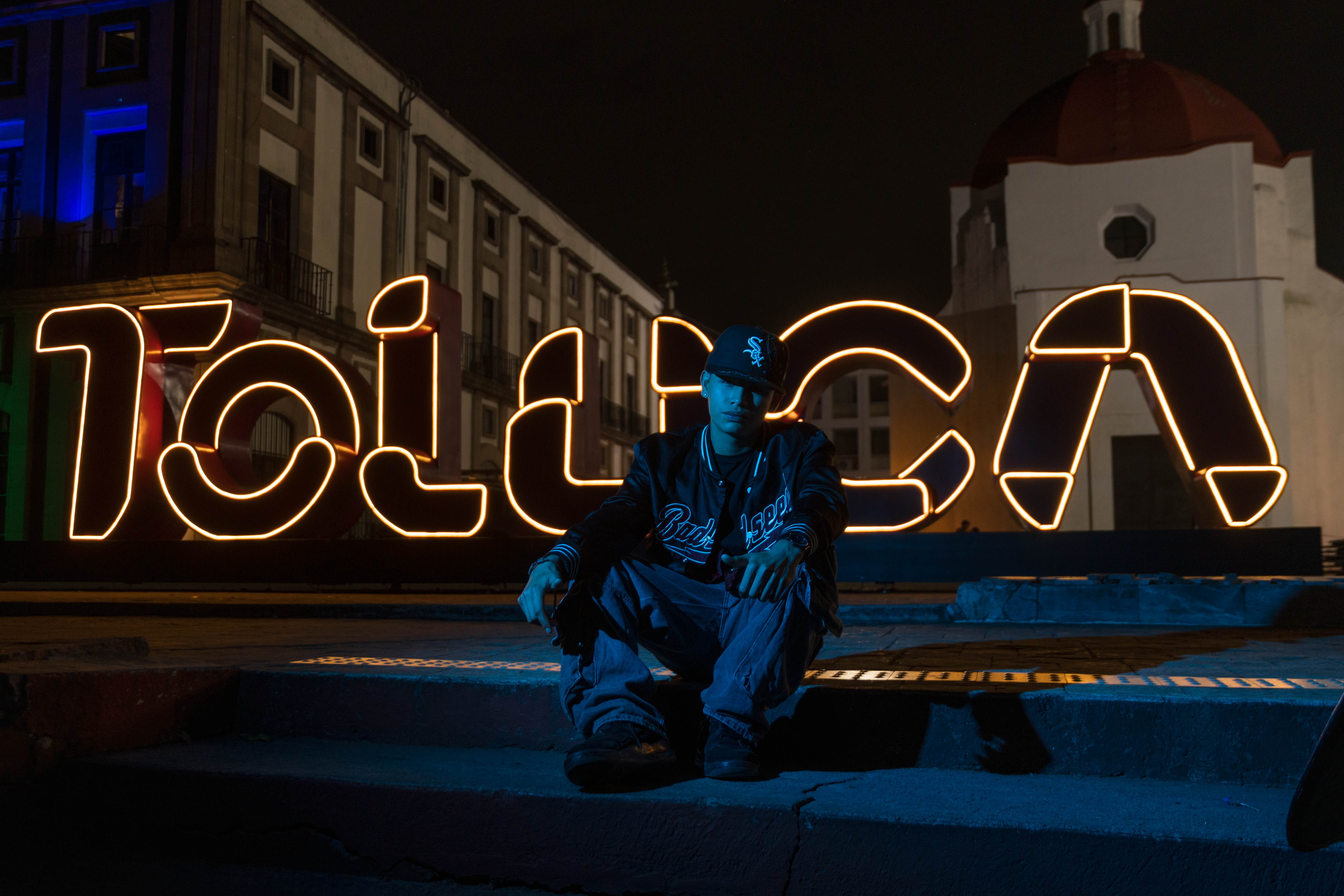 Astro frente a las letras neón de Toluca